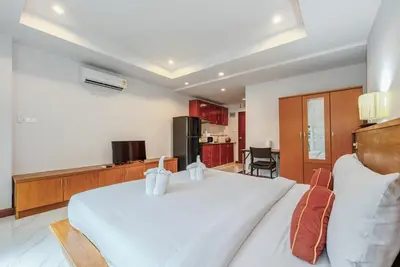 a bedroom with a large white bed and a kitchen at C200 Relaxing 1BR Stay Walk to Nai Harn Beach in Rawai Beach