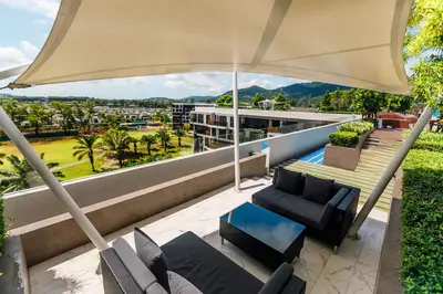 a patio with chairs and an umbrella on a building at Cozy studio Laguna SkyPark Phuket in Laguna Phuket