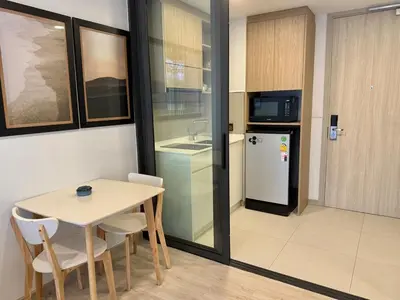 a small kitchen with a table and a refrigerator at Laguna SkyPark by ShowProperty in Laguna Phuket