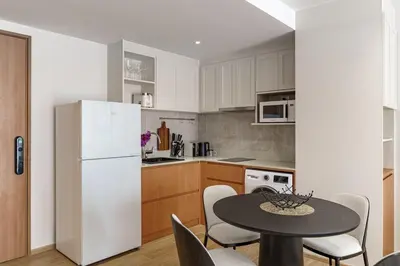a kitchen with a table and a white refrigerator at Laguna Beachside by ShowProperty in Bang Tao Beach