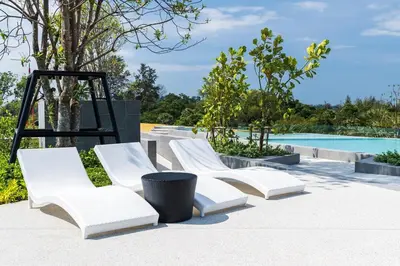 a group of white chairs sitting next to a pool at Laguna Beachside by ShowProperty in Bang Tao Beach