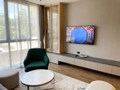 a living room with a green chair and a tv at Layan Green Residence by ShowProperty in Layan Beach