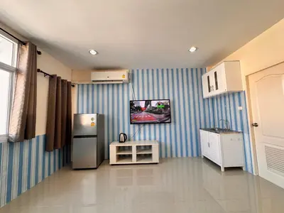 a kitchen with a refrigerator and a tv on the wall at Tropikathu Guest House in Kathu