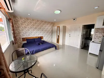 a bedroom with a bed and a table and a kitchen at Tropikathu Guest House in Kathu