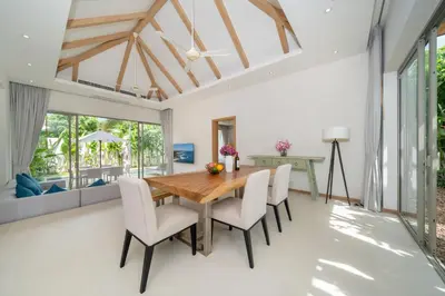 a dining room with a wooden table and white chairs at 3 Bedroom Villa with Private pool in Laguna Phuket