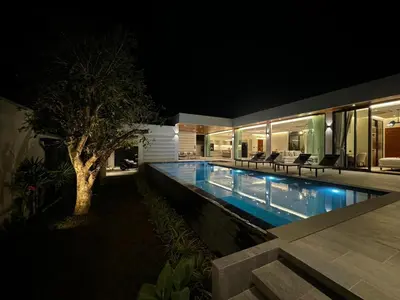 a house with a swimming pool at night at The Nature Villa Phuket in Rawai Beach