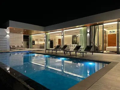 a house with a swimming pool at night at The Nature Villa Phuket in Rawai Beach