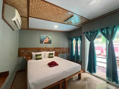 a bedroom with a white bed with blue curtains at Phi Phi Ingphu Viewpoint Hotel in Phi Phi Don