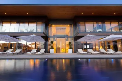 a building with chairs and umbrellas in front of a pool at Cliff Top Residence in Phuket Town