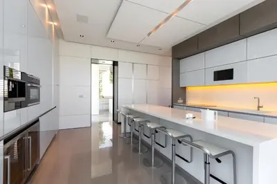 a kitchen with white cabinets and a long counter with stools at Cliff Top Residence in Phuket Town