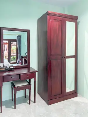 a wooden cabinet next to a desk with a mirror at Sun-San Thalane Resort in Ban Laem