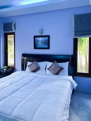 a large white bed in a bedroom with blue walls at Sun-San Thalane Resort in Ban Laem