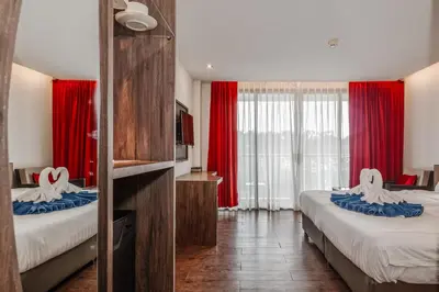 a hotel room with two beds with red curtains at C202 Sun and Fun Kids Club 1BR 500m to Beach in Kata Beach