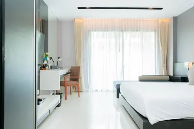a bedroom with a bed and a desk and a window at Beachfront 1 BR Hotel Infinity Pool Patong Phuket in Patong Beach