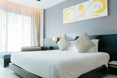 a bedroom with a large white bed and a window at Beachfront 1 BR Hotel Infinity Pool Patong Phuket in Patong Beach