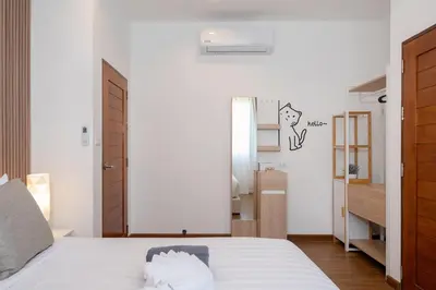 a bedroom with a bed with white sheets and a mirror at Kamala Sunshine Villa - Goldena Twin in Kamala Beach