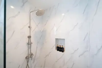a shower in a bathroom with white marble walls at Kamala Sunshine Villa - Goldena Twin in Kamala Beach
