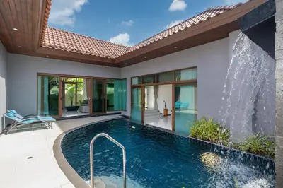 an indoor swimming pool in a house with a waterfall at Ocean Palms Private Pool Villas in Ban Thalat Choeng Thale