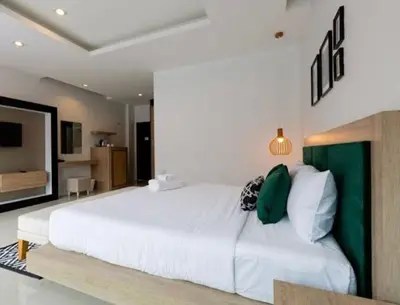 a bedroom with a large white bed with green accents at The Kris Luxury in Patong Beach