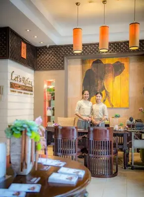 two people standing in a restaurant with tables and chairs at The Kris Luxury in Patong Beach