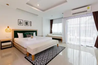 a white bedroom with a large bed and a window at The Kris Luxury in Patong Beach