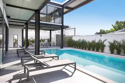 a swimming pool with chaise lounge chairs next to a house at New 2-Storey Villa Sunset Garden 8 with 4BR & Eco-Pool, near Naiharn in Rawai Beach