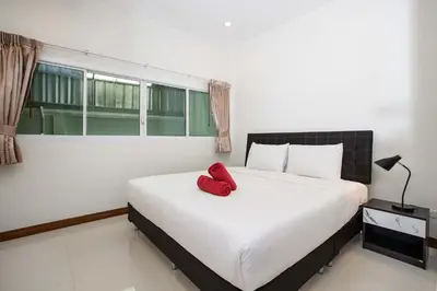 a bedroom with a bed with a red pillow on it at Family 2BR Villa Lancelot 3 with Jacuzzi Pool, just 10 min drive NaiHarn and Rawai in Rawai Beach