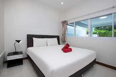 a bedroom with a large bed with a red pillow on it at Family 2BR Villa Lancelot 3 with Jacuzzi Pool, just 10 min drive NaiHarn and Rawai in Rawai Beach