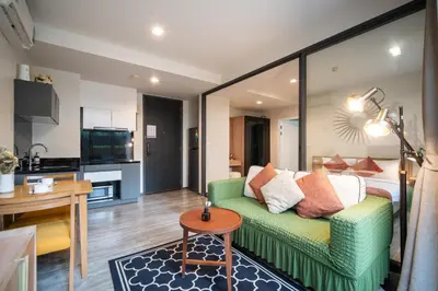 a living room with a green couch and a kitchen at \u82ad\u4e1cThe DECK 6\u516c\u5bd3 \u8fd1\u82ad\u4e1c\u6d77\u6ee9BANGLA\u6c5f\u897f\u51b7 in Patong Beach