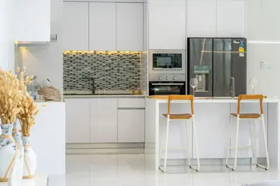 a kitchen with white cabinets and two bar stools at The Residence Tropical 3BR Villa with Private Pool in Ban Pak Lak