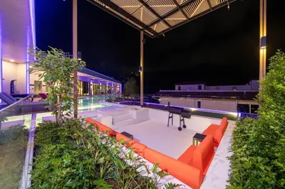 a swimming pool at night with orange furniture at Elite Villa Patong Phuket in Patong Beach