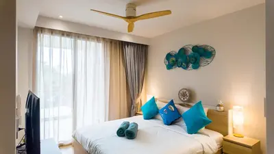 a bedroom with a bed with blue pillows and a window at Beachside Residence 4 floor, Seaside, 250m to the beach in Bang Tao Beach