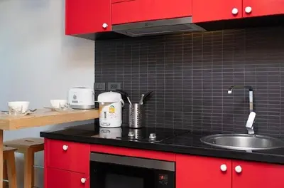 a kitchen with red cabinets and a sink at Relife 5 mins walk to the beach in Rawai Beach