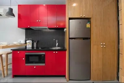 a kitchen with red cabinets and a refrigerator at Relife 5 mins walk to the beach in Rawai Beach