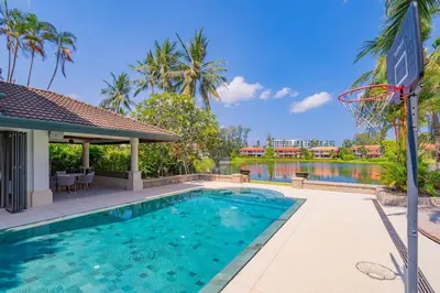 a swimming pool with a basketball hoop next to a lake at 4BR Lakeshore Pool Villa in Laguna Bangtao in Bang Tao Beach