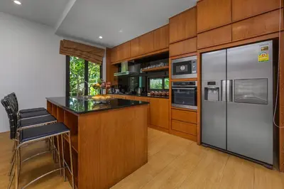 a kitchen with wooden cabinets and stainless steel appliances at Villa Fam with Private Pool Near Nai Harn Beach in Rawai Beach