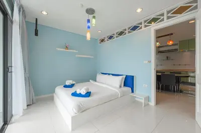 a bedroom with a white bed and a blue wall at C205 4BR Pool, Mountain Views & Prime Location in Kamala Beach