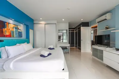 a bedroom with a large white bed and a flat screen tv at C205 4BR Pool, Mountain Views & Prime Location in Kamala Beach