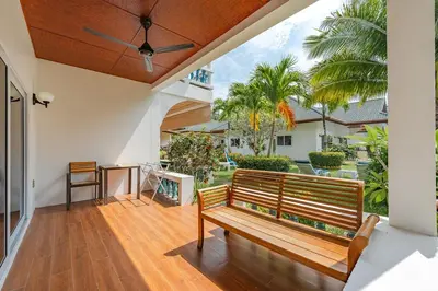 a wooden bench on a porch with palm trees at V205 Island Hideaway Near Promthep Sunset in Nai Harn Beach