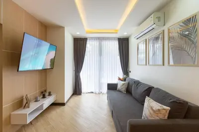 a living room with a couch and a flat screen tv at Calipso Garden 108 in Rawai Beach