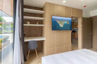 a bedroom with a flat screen tv on a wall at Calipso Garden 108 in Rawai Beach