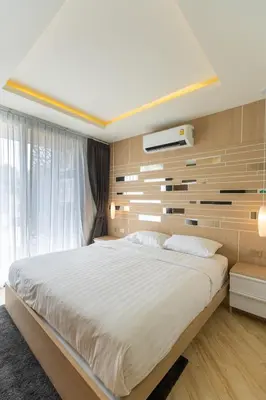 a bedroom with a large white bed and a wall at Calipso Garden in Rawai Beach