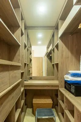 a walk in closet with wooden cabinets and a stool at Calipso Garden in Rawai Beach