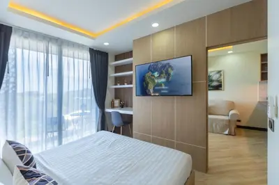 a bedroom with a bed and a tv on a wall at Calipso Garden 304 in Rawai Beach