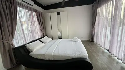a bedroom with a large bed in front of windows at Spacious 3 bedroom townhouse in Laguna in Laguna Phuket