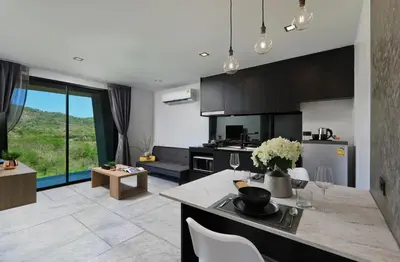 a kitchen with black cabinets and a table with chairs at \u4e5d\u96c5\u96c6 The Nine Refined Retreats in Rawai Beach
