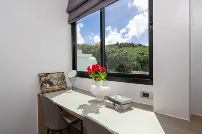 a dining room table with a vase of flowers and a window at \u4e5d\u96c5\u96c6 The Nine Refined Retreats in Rawai Beach