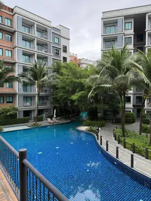 a swimming pool with palm trees and buildings at The title Naiyang - Beach Condos in Nai Yang Beach