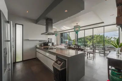 a kitchen with a counter and a dining room with tables at V203 Seahorse Villa Stunning 4BR Oceanview Retreat in Bang Tao Beach