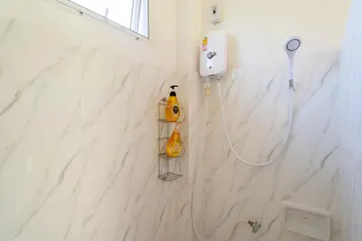 a white bathroom with a shower with a yellow device on the wall at Villa Prima - 3 Bedroom Private Pool Villa in Rawai Beach
